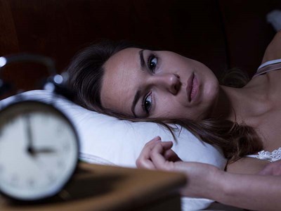 Neurofeedback Insomnia: A woman laying awake because she either can't fall asleep or stay asleep, but Neurofeedback may help!